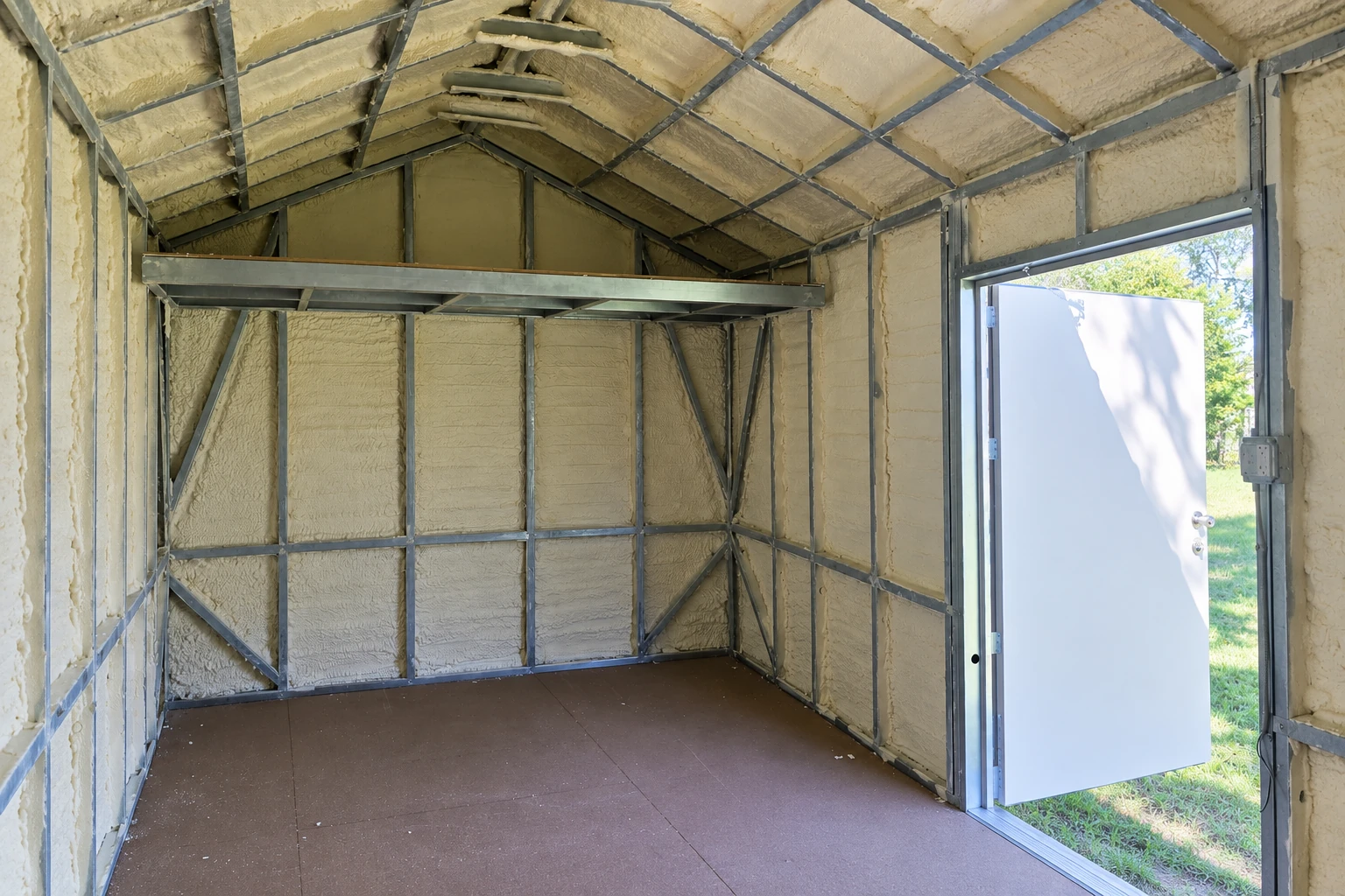 Spray foam coats the walls and ceiling of a metal-framed commercial room beside an open door.